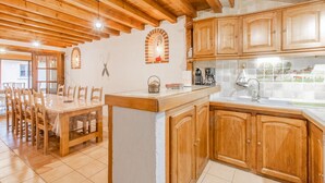 A kitchen with wooden cabinets, a tiled backsplash, and a dining area with a wooden table and chairs. - Domaine du Venet - Montcony (MONTCONY)