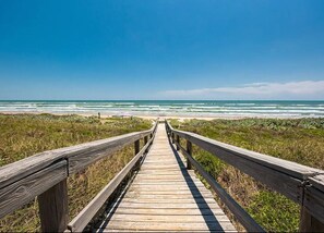 A wooden boardwalk leading to the beach with a clear view of the ocean.