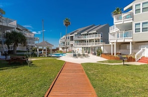 Um hotel à beira-mar com várias varandas, área de piscina e um calçadão de madeira que leva à piscina.
