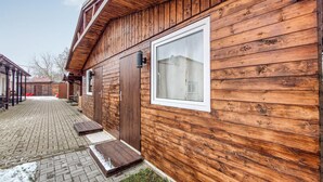 A wooden cabin with a large window, a covered patio, and a brick pathway.