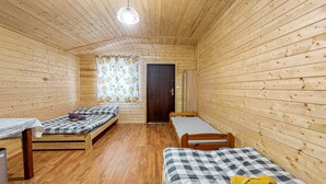 A small, cozy room with wooden walls and floors, featuring two single beds and a small table.