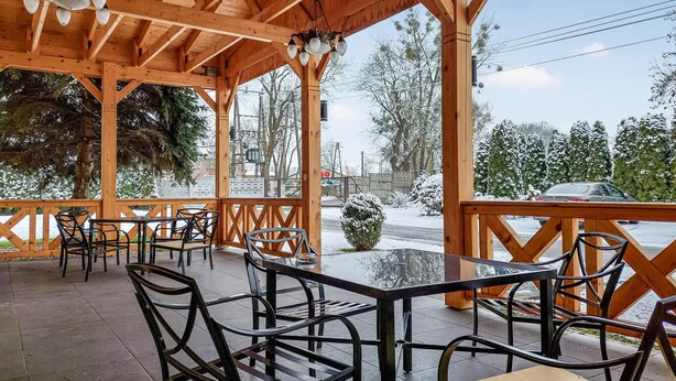 A wooden outdoor seating area with tables and chairs, overlooking a snowy landscape.