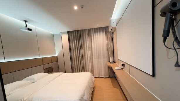 Een hotelkamer met een bed, een kaptafel met spiegel, een haardroger en een gordijn.