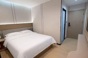 Een moderne hotelkamer met een groot bed, een inbouwkast en een deur naar een badkamer.