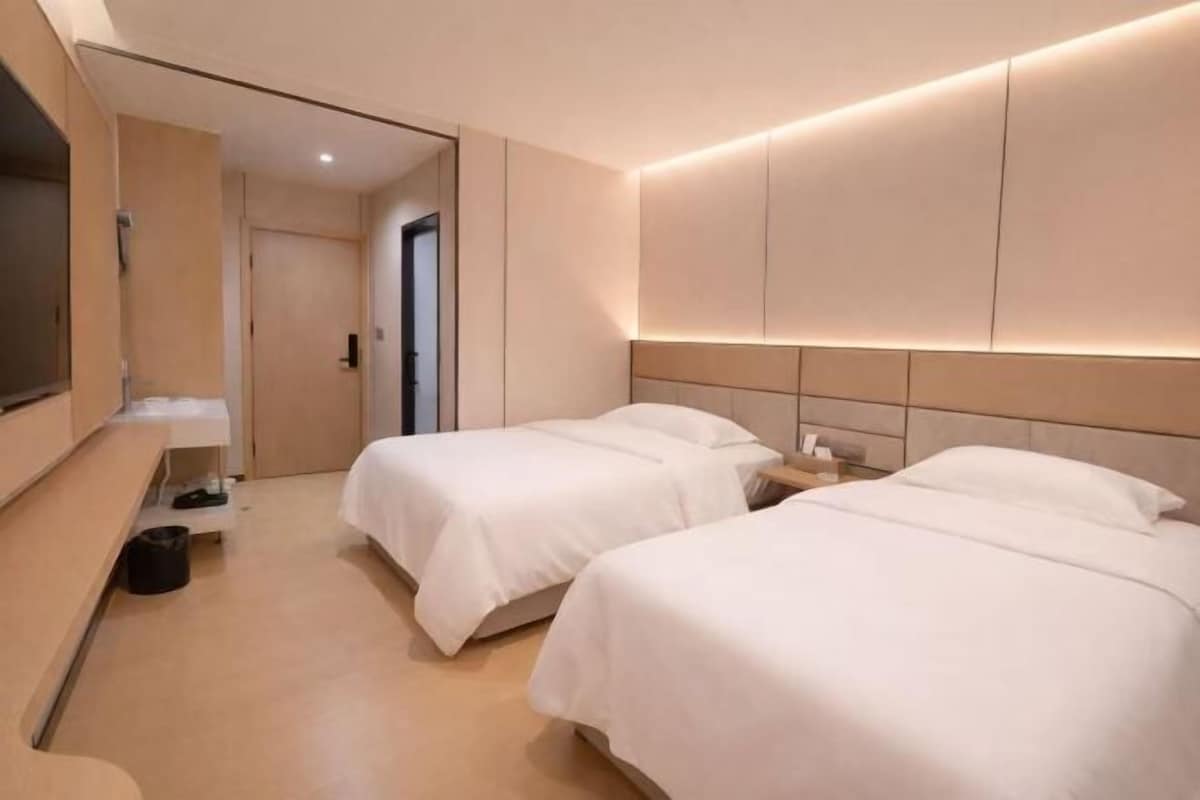 Une chambre d’hôtel avec deux lits, une télévision et un bureau.
