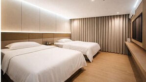 Een hotelkamer met twee bedden, een grote spiegel, een flatscreen-tv en een raam met gordijnen.