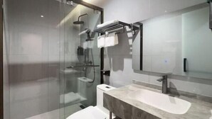 Een moderne badkamer met een douchecabine van glas, een wit toilet, een marmeren wastafel en een grote spiegel.