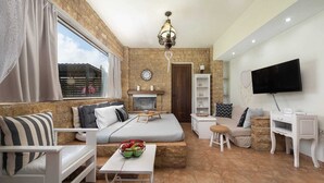 A furnished living room with a sofa, a small table with fruit, a television, and a fireplace.