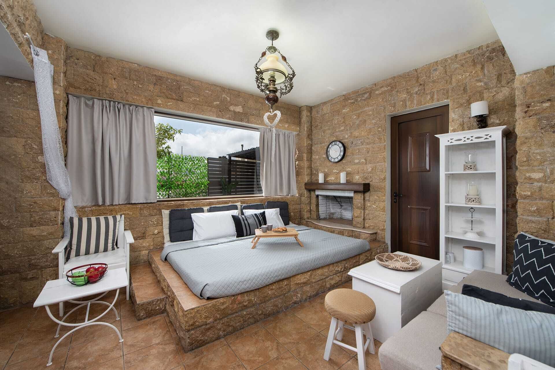 Een slaapkamer met een bed, een klein tafeltje, een stoel, een boekenkast en een open haard.