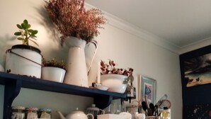 Una cocina con estantes que sostienen vajilla, un cartel de Volkswagen y un cartel de Pontiac.