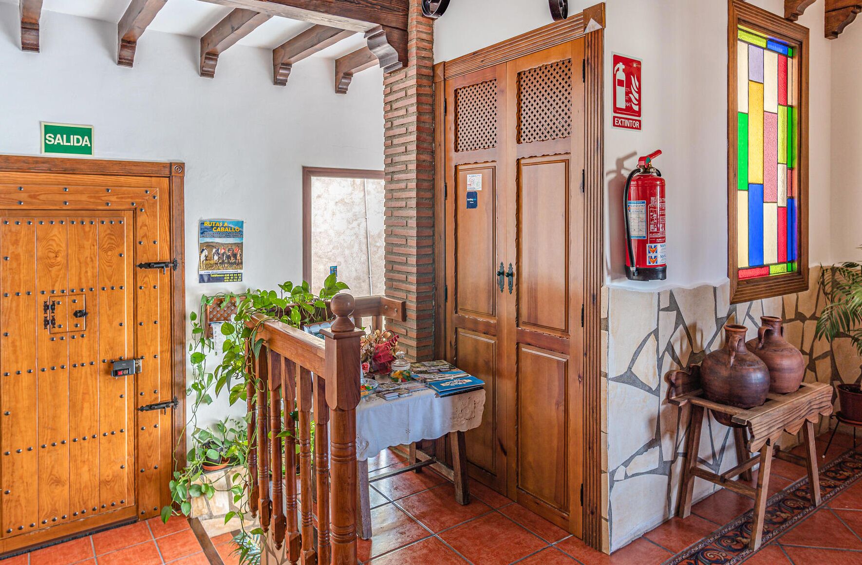 Un pasillo con puertas de madera, un extintor, un cartel que dice "SALIDA" y un suelo de baldosas.