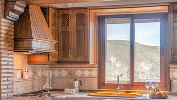 A kitchen with wooden cabinets, a large window, and a view of a hilly landscape.