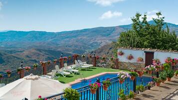 A pool area with lounge chairs and a view of mountains.