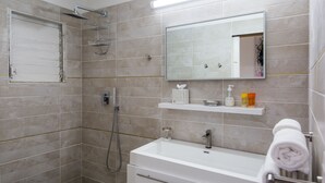 Ein modernes Badezimmer mit Dusche, Waschbecken und Spiegel.