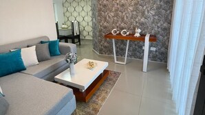 A modern living room with a grey sofa, a white coffee table, and a patterned wall. - Apartamento en moca (Moca)