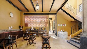 A lobby with wooden chairs, a reception desk, a staircase, and a decorative wall. - Colmena Hotel CDMX Centro (Mexico City)