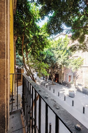 A courtyard with a stone bench, a metal railing, and trees. - Colmena Hotel CDMX Centro (Mexico City)