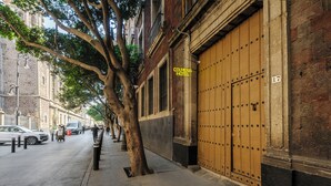 A street view with a building labeled 'Colmena Hotel,' featuring a large wooden door and a tree-lined sidewalk. - Colmena Hotel CDMX Centro (Mexico City)