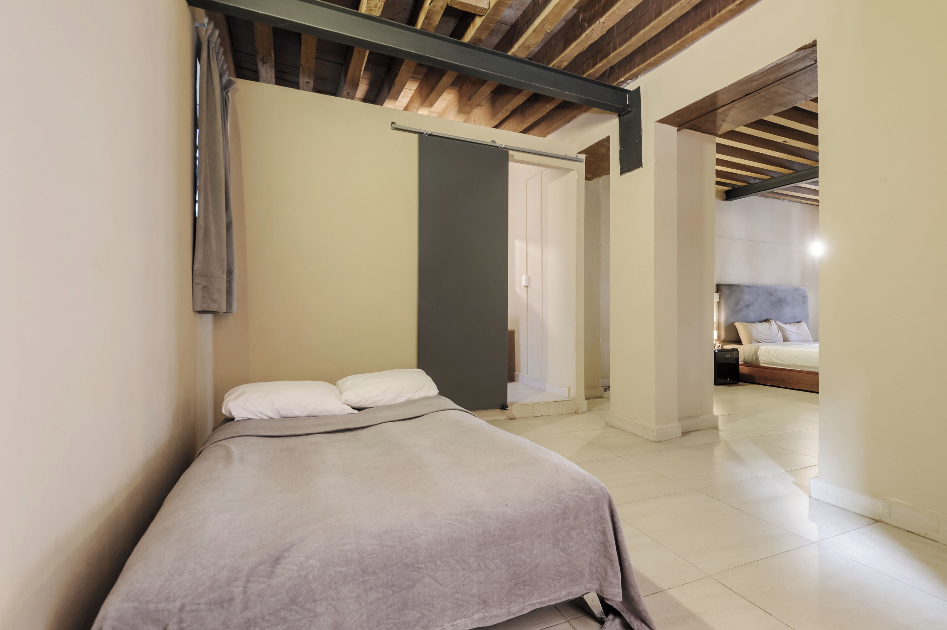 A bedroom with a bed, a wardrobe, and a door leading to another room.