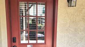 A red door with a glass panel, a number plate, and a wall-mounted light fixture. - Alan's Apartment - Hot tub, fireplace, located in a quiet corner of Helen. (Helen)