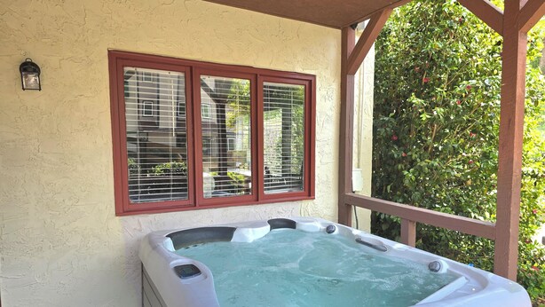 A hot tub under a pergola with a window and a wall-mounted light. - Alan's Apartment - Hot tub, fireplace, located in a quiet corner of Helen. (Helen)
