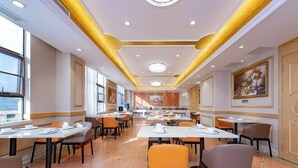 A spacious restaurant with multiple tables and chairs, a high ceiling with recessed lighting, and large windows allowing natural light. - Vienna International Hotel (Xinhua)
