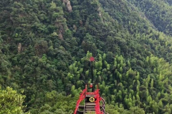 A traditional Chinese pagoda with a red roof, surrounded by dense forest. - Vienna International Hotel (Xinhua)