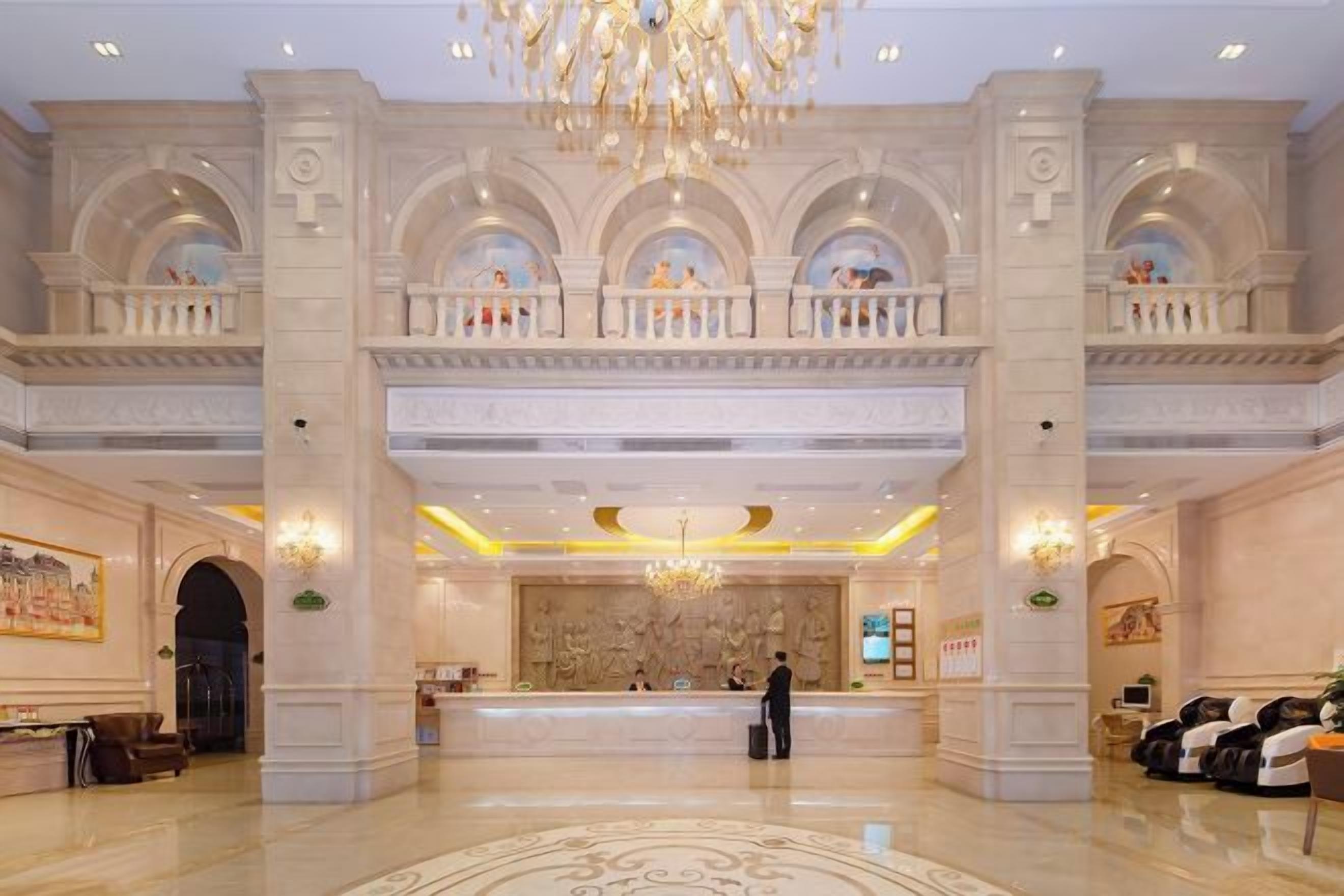 A grand lobby with a reception desk, high ceilings, and a chandelier.
