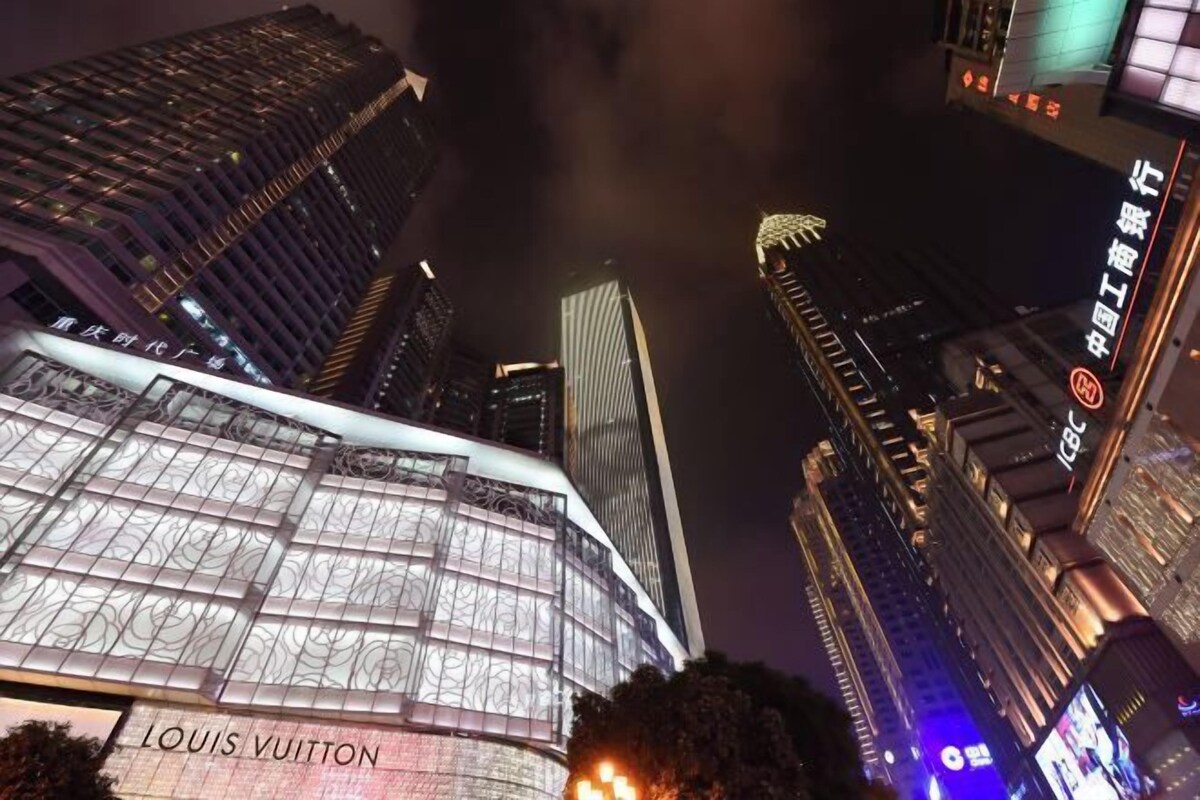 A high-rise building with illuminated signage and a prominent Louis Vuitton store at its base.