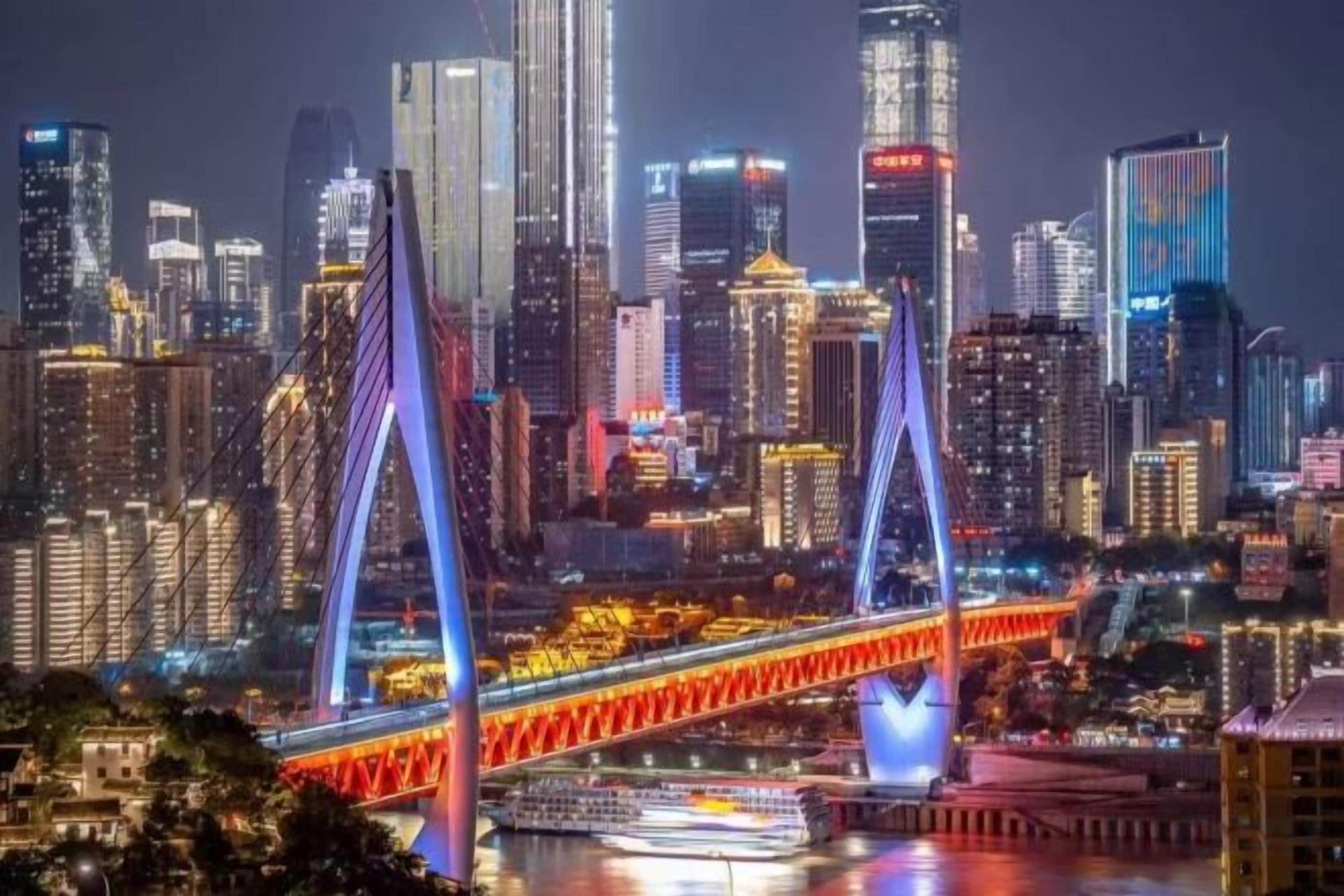 A cityscape with a prominent bridge and illuminated skyscrapers.