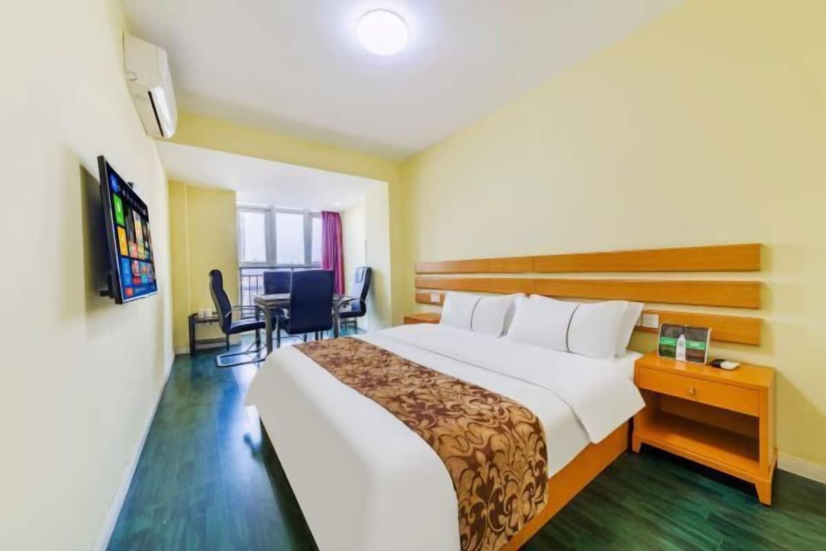 A hotel room with a bed, bedside table, and a desk with a chair.