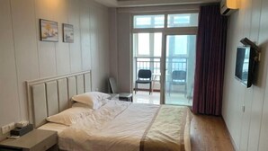 A hotel room with a bed, a nightstand, a TV mounted on the wall, and a balcony with a chair.