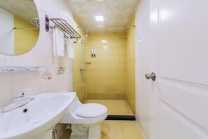 A small bathroom with a white sink, toilet, and a shower stall.