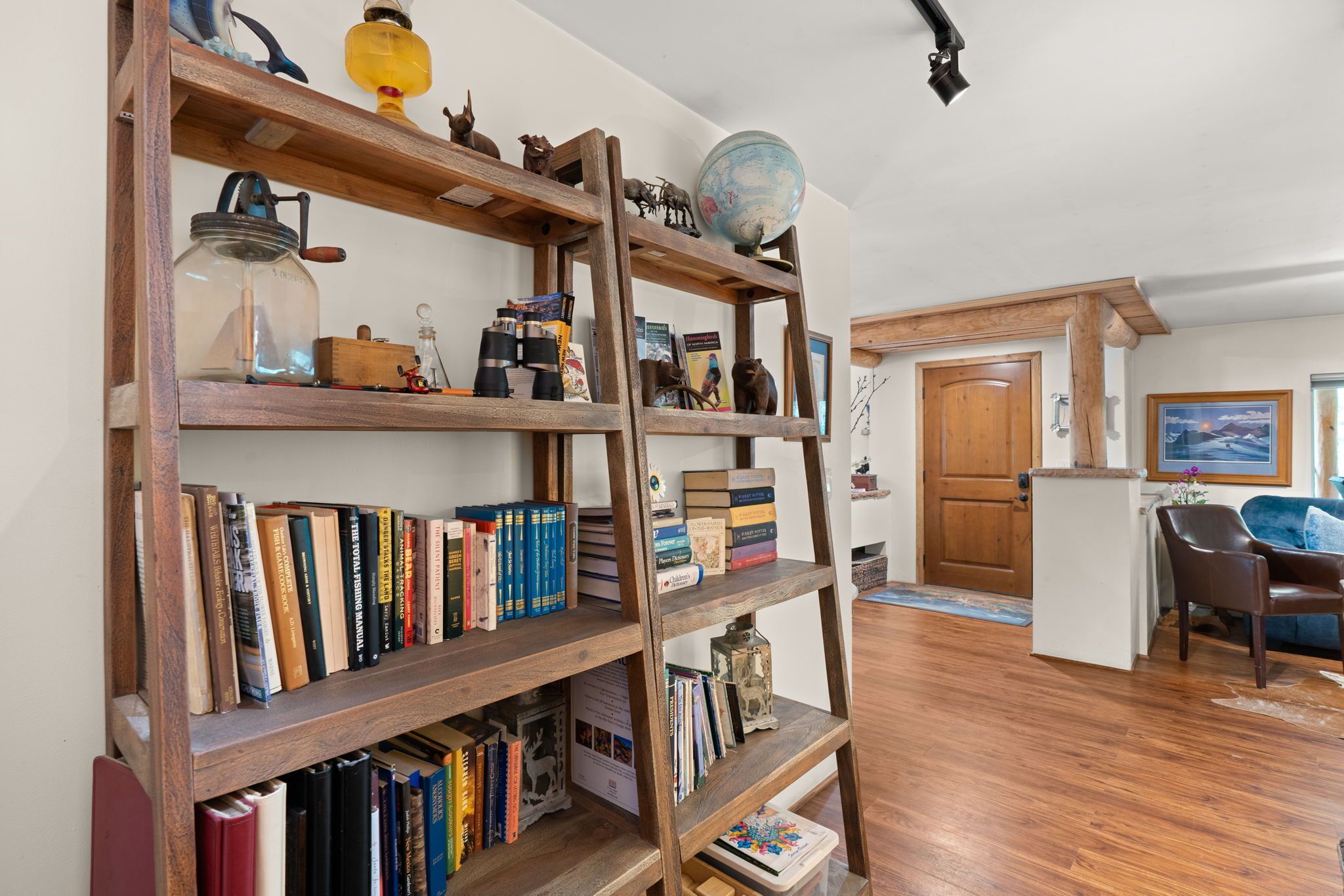 A wooden bookshelf filled with books and decorative items, a globe, and a vintage milk can.