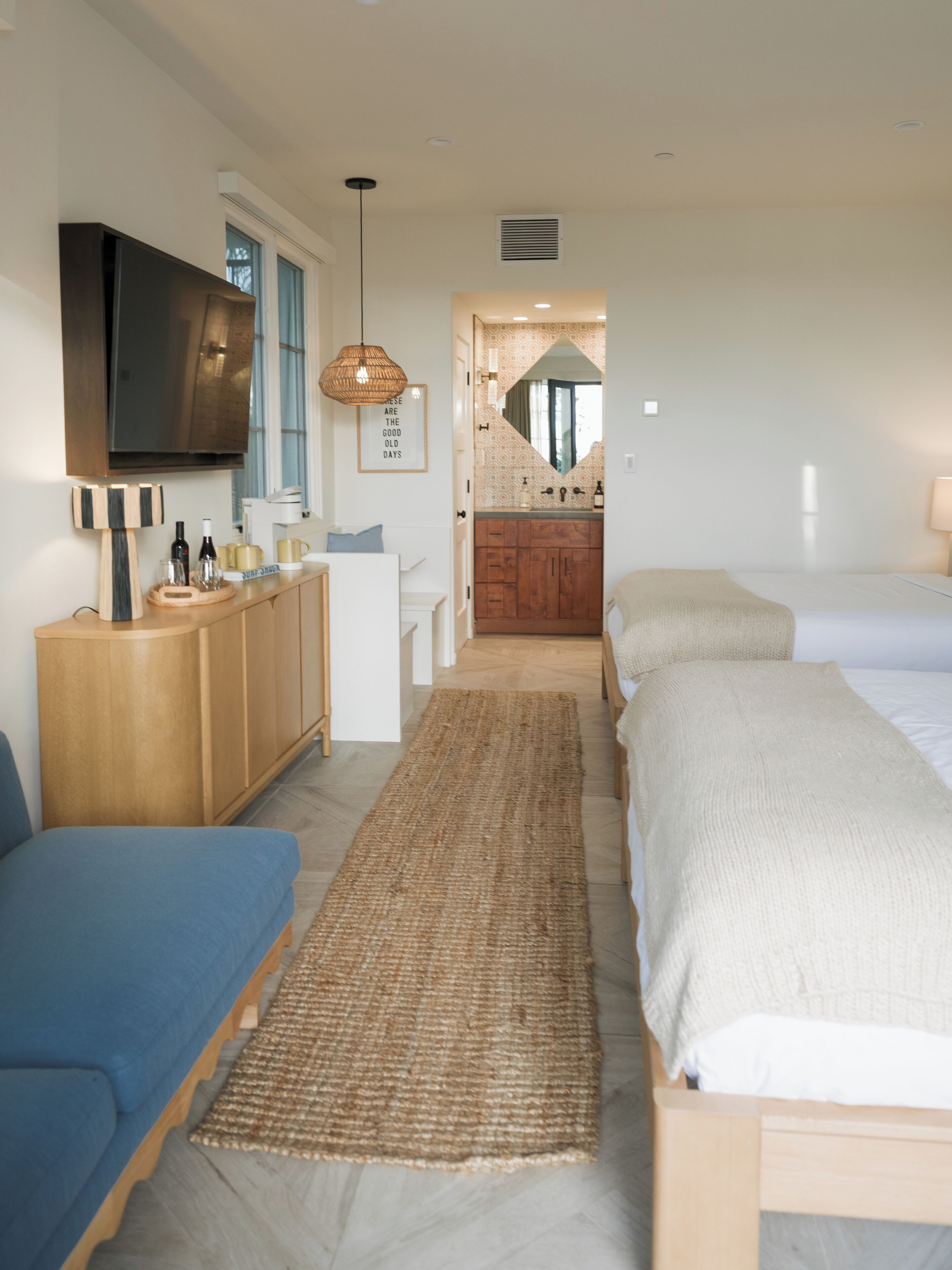 Une chambre moderne avec un grand lit, un canapé, une commode en bois et un téléviseur.