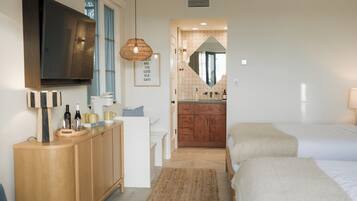 Une chambre moderne avec un grand lit, un canapé, une commode en bois et un téléviseur.