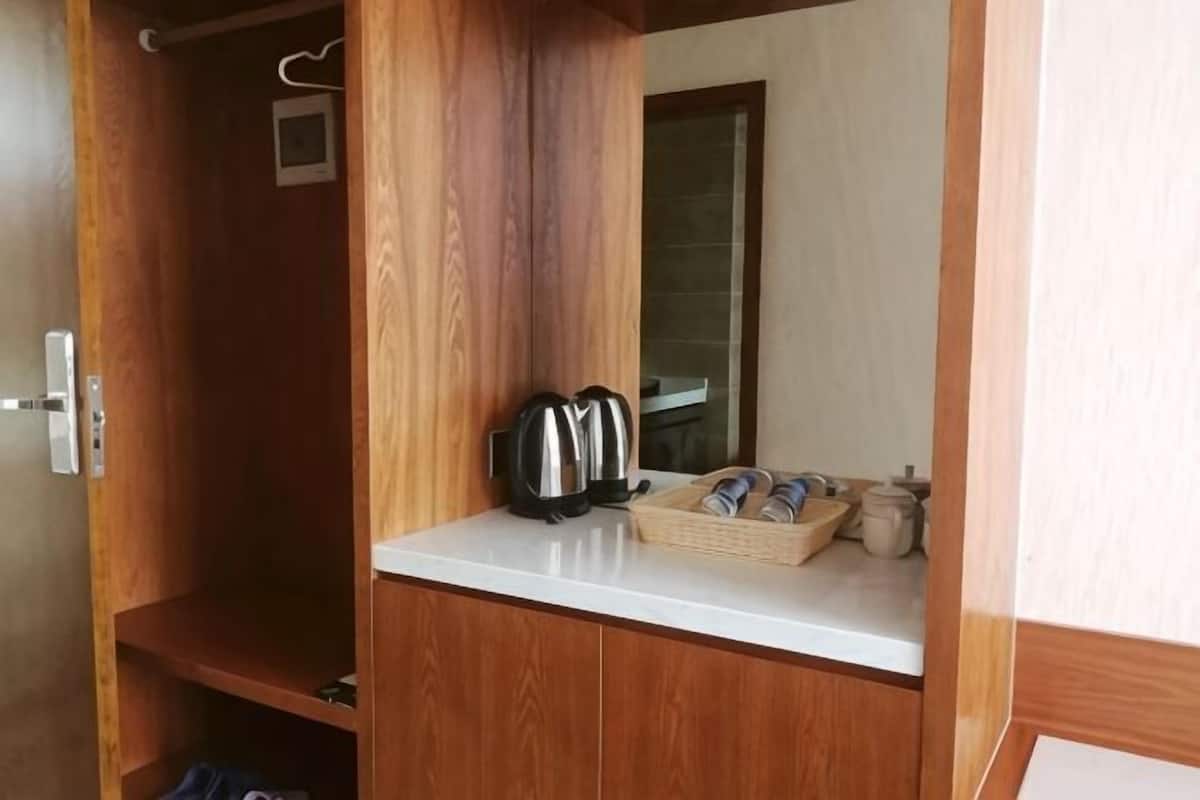 Um guarda-roupa de madeira com bancada branca, chaleira e uma cesta de toalhas.