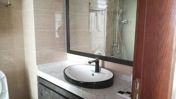 A bathroom with a round sink, a mirror, and a shower.