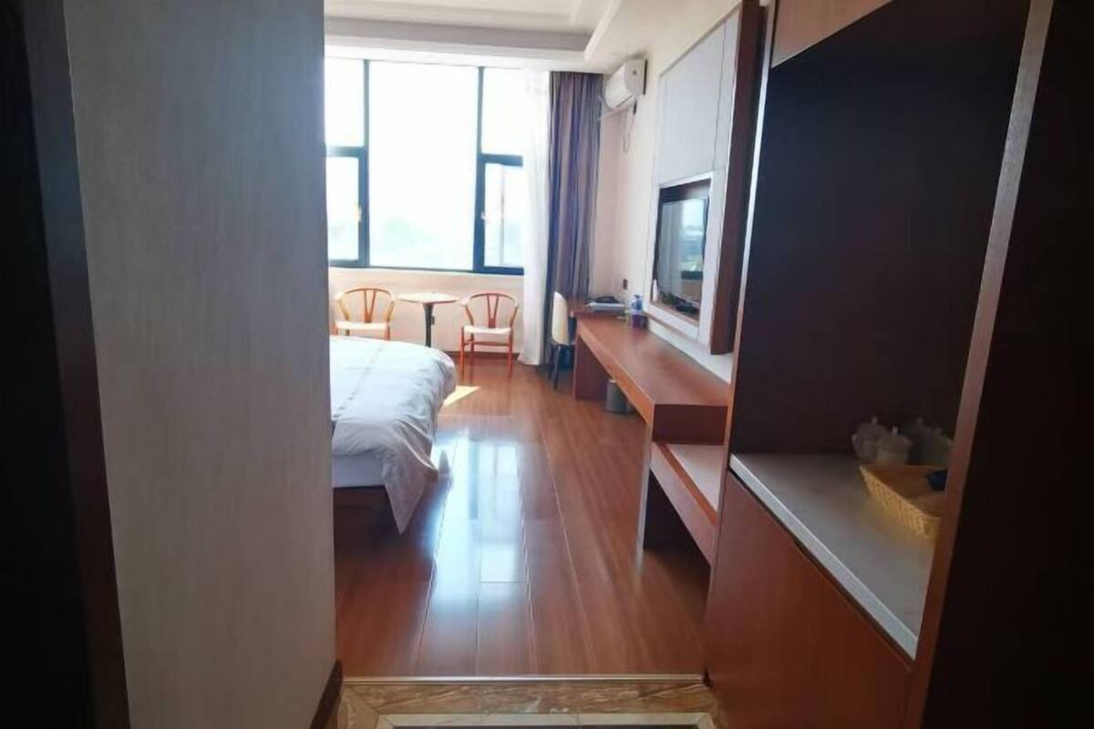Quarto de hotel com cama, escrivaninha, televisão e janela.