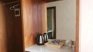 A wooden interior with a white countertop, two kettles, a basket of rolled-up towels, and a small window. - Liangzhou Hotel (Luliang)
