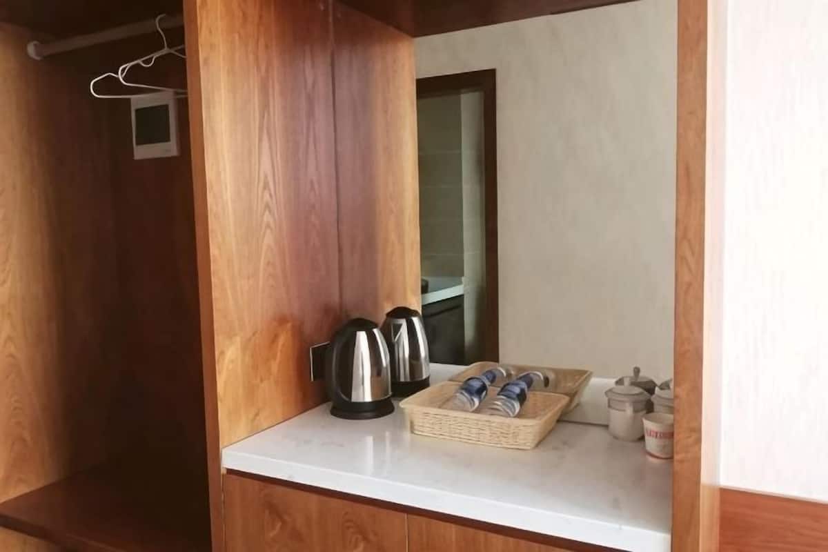 Interior em madeira com bancada branca, duas chaleiras, uma cesta com toalhas dobradas e uma janela pequena.