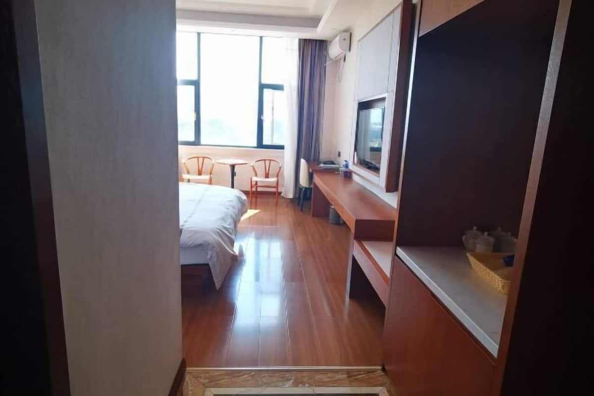 Quarto de hotel com cama, televisão, escrivaninha e janela.