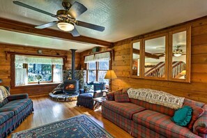 Cozy living room with a central fireplace, comfortable sofa, and large window offering a view of the outdoors.