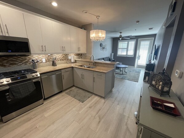 Cozinha moderna com eletrodomésticos de aço inoxidável, uma ilha central e um lustre.