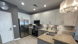 A modern kitchen with stainless steel appliances, granite countertops, and a microwave.
