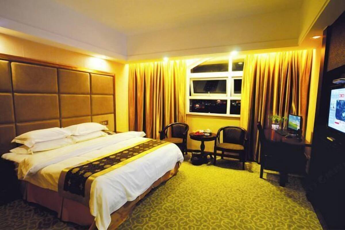Une chambre d’hôtel avec un lit, un bureau, une chaise, une petite table et un téléviseur.