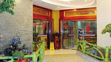 A hotel lobby with a stone wall, a decorative bridge, and a glass door entrance.