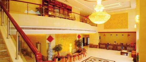 A hotel lobby with a grand staircase, a chandelier, and a decorative floor pattern.