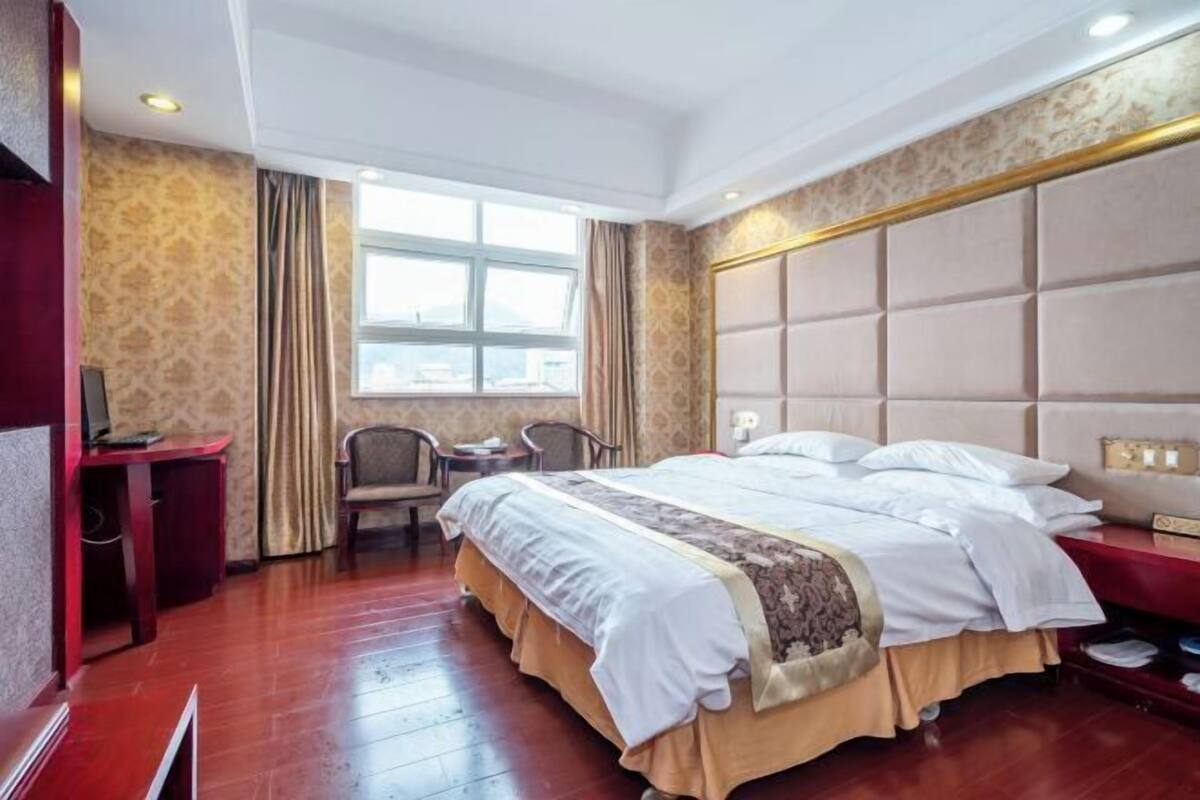 Une chambre d’hôtel avec un grand lit, un bureau, une chaise et une fenêtre avec des rideaux.