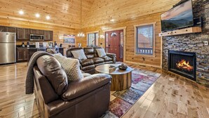 Una sala de estar acogedora con chimenea, sofá de cuero y piso de madera.